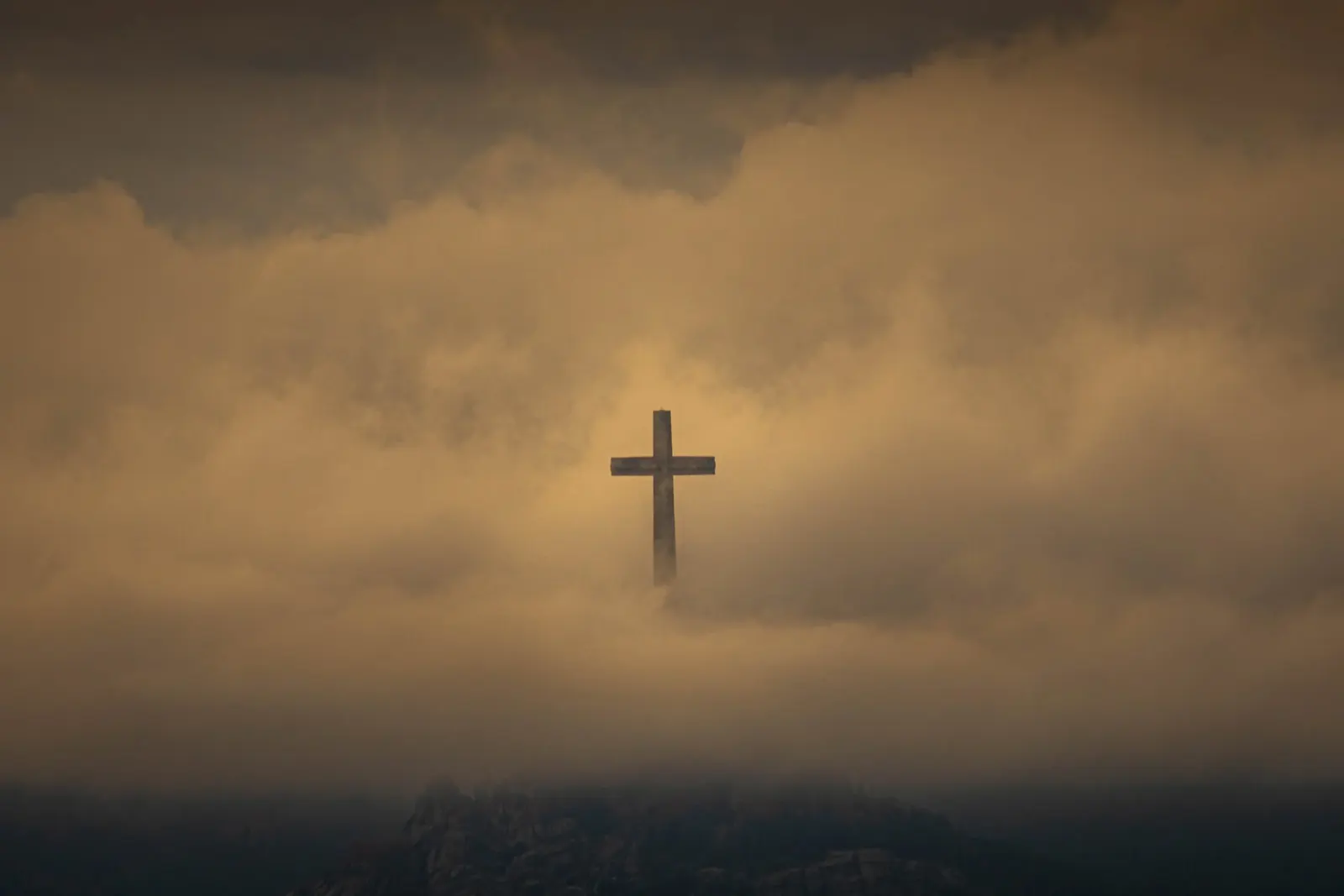 A cross on a hill beneath a glowing sky